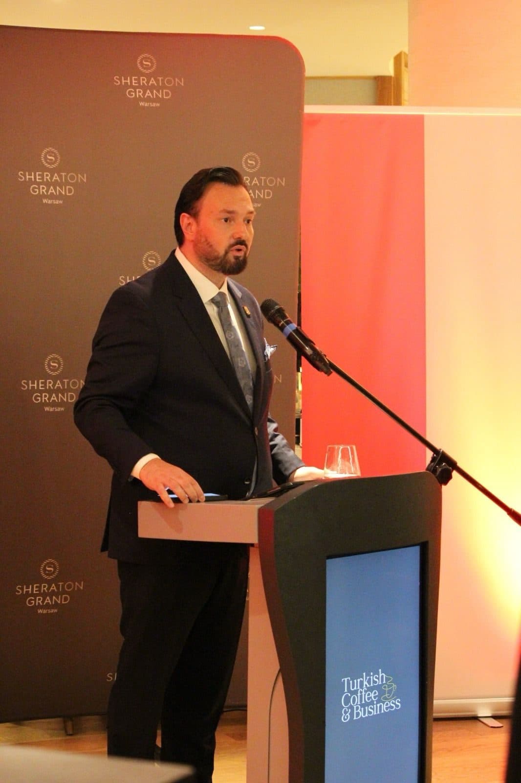 The host speaking at a lectern during the reception