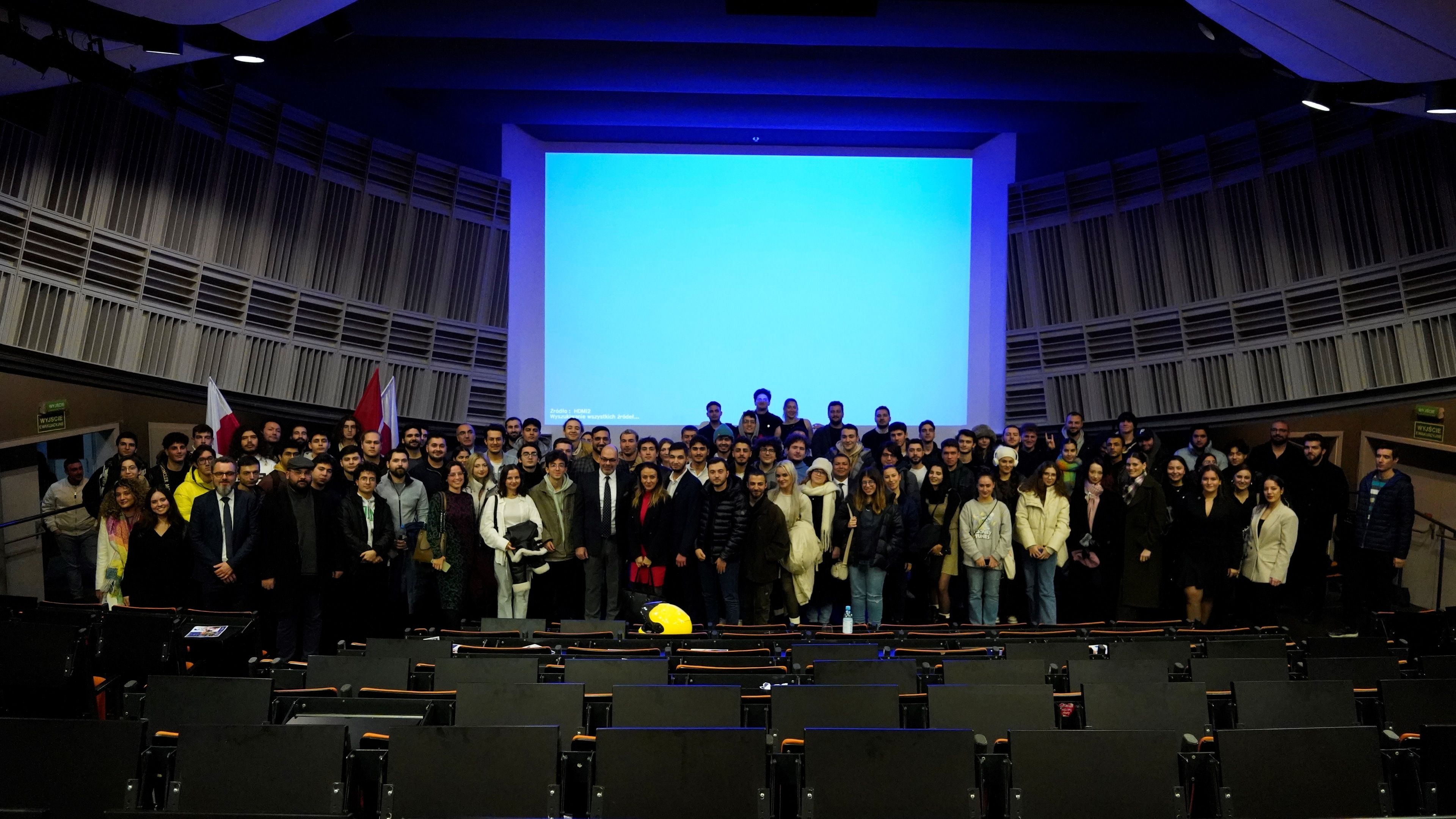 Wide group photograph of TURKPOL members and guests gathered in an auditorium at a bilateral festival, Polish and Turkish flags visible behind the stage.