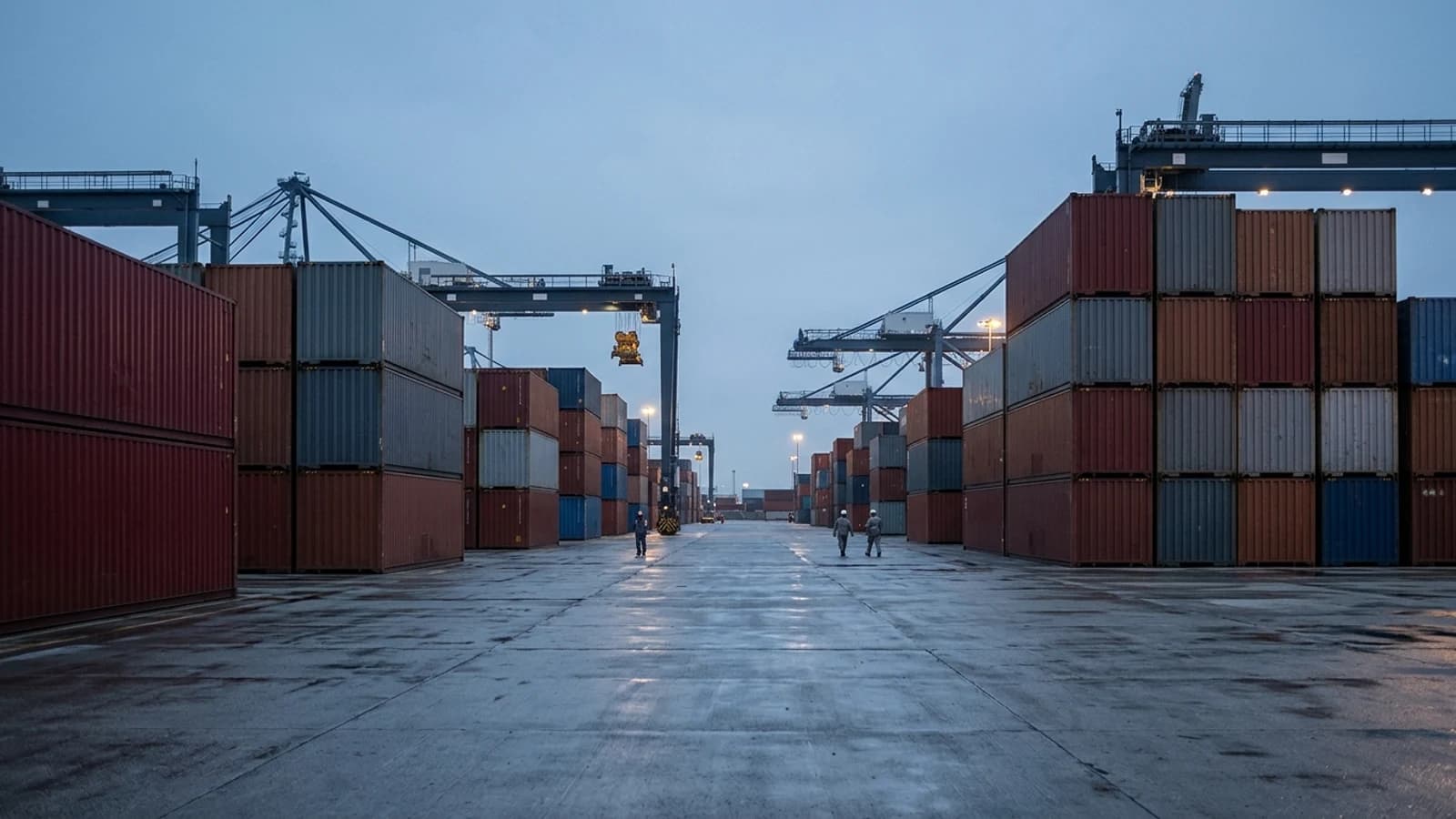 A container terminal at blue hour: stacked shipping containers, gantry cranes in silhouette, wet concrete.